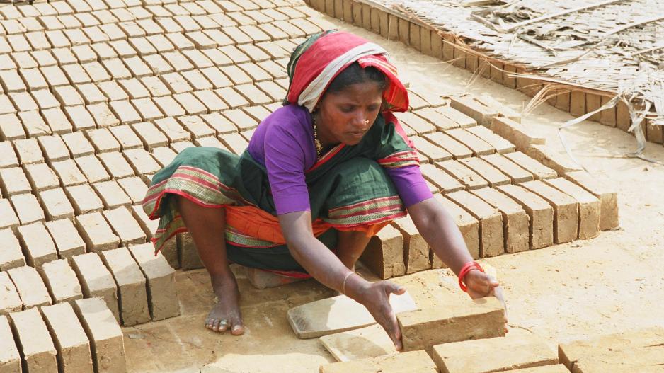 Eine Frau stapelt handgeformte Ziegel